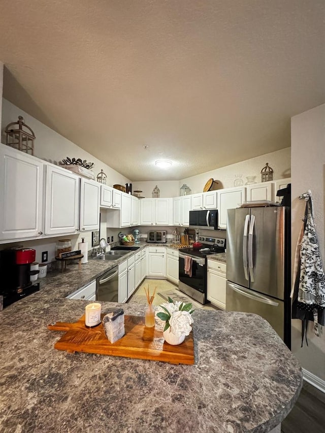 kitchen featuring a sink, a textured ceiling, white cabinets, and stainless steel appliances