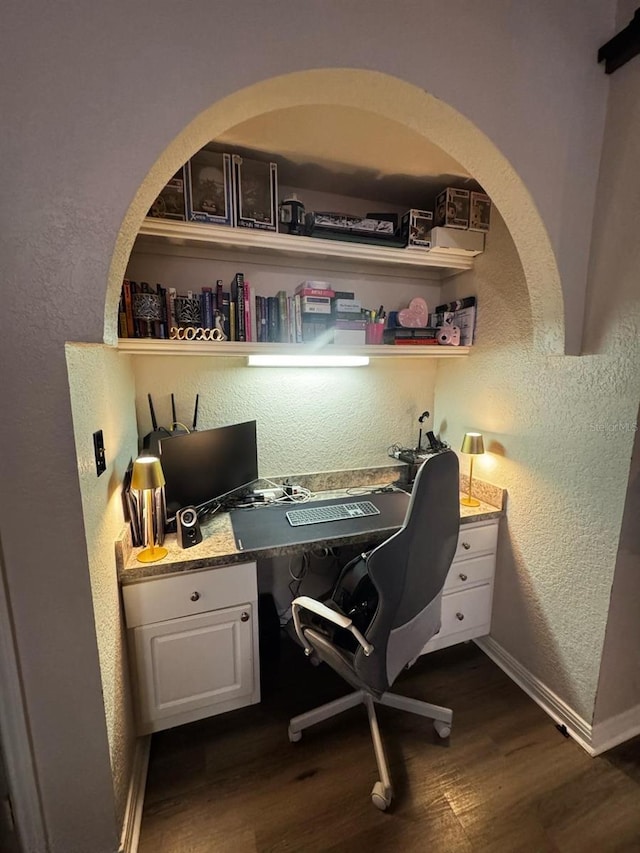 office area featuring dark wood-style floors, baseboards, a textured wall, and built in study area