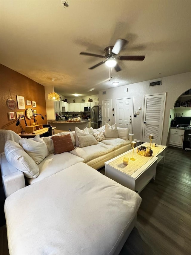 living area featuring visible vents, dark wood-type flooring, and a ceiling fan