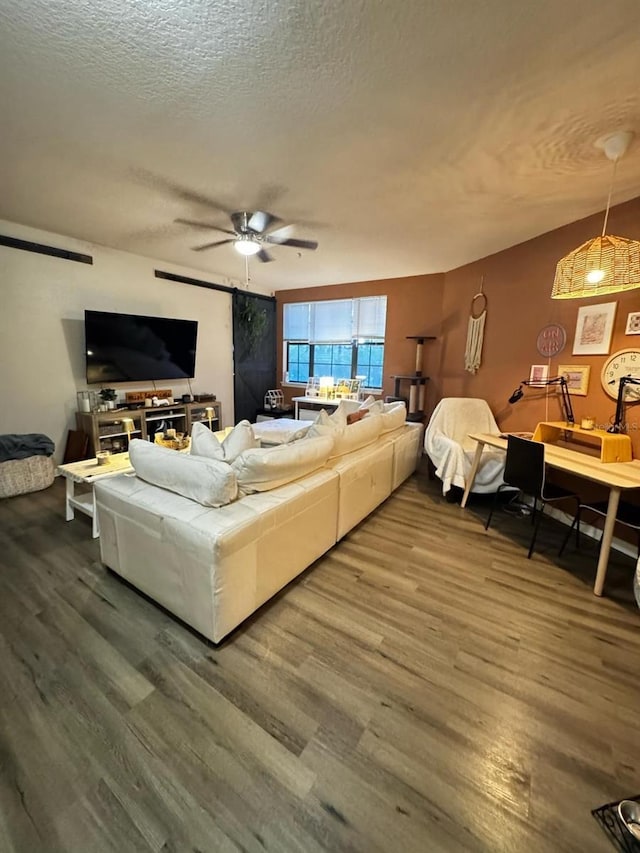 living area with dark wood finished floors, ceiling fan, and a textured ceiling