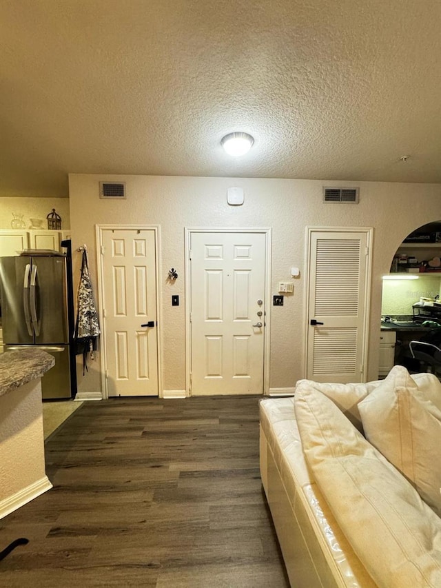 interior space with visible vents, a textured ceiling, and dark wood finished floors