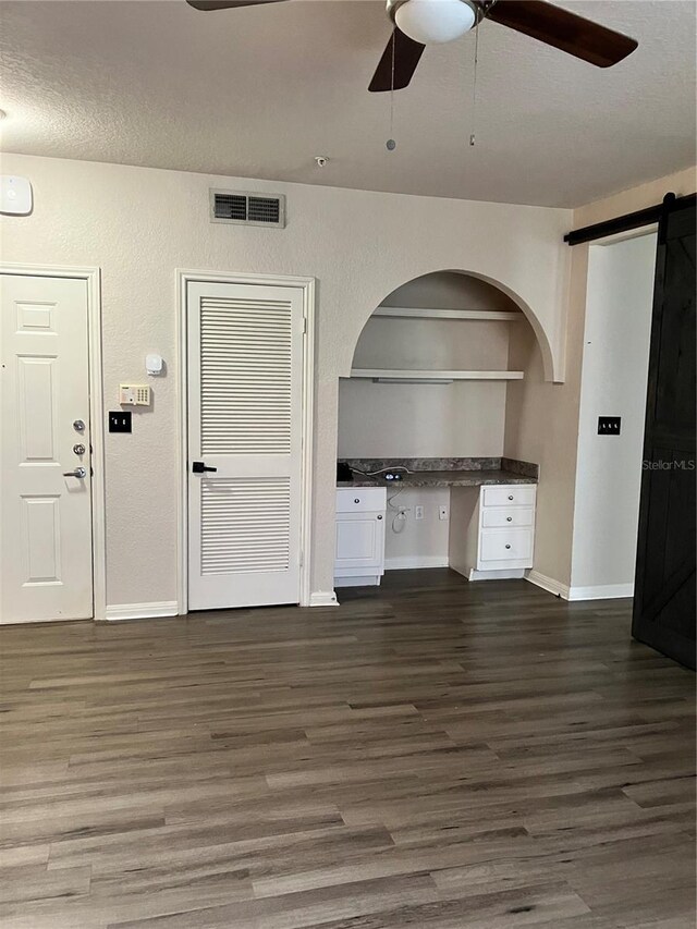 911 N Orange Ave Unit 142, Orlando, FL 32801 - unfurnished living room featuring dark wood finished floors, ceiling fan, baseboards, a barn door, and a textured ceiling