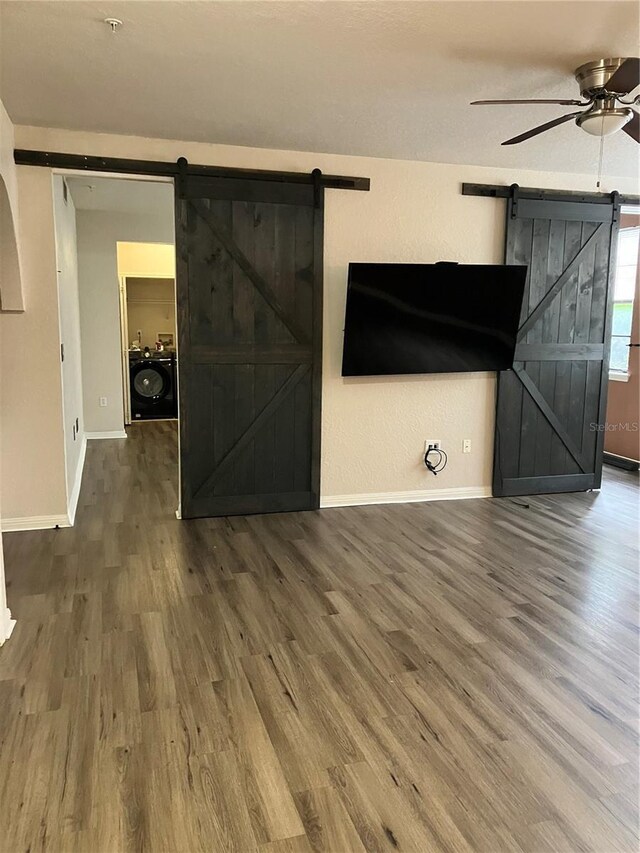 911 N Orange Ave Unit 142, Orlando, FL 32801 - unfurnished living room featuring a barn door, wood finished floors, ceiling fan, and baseboards