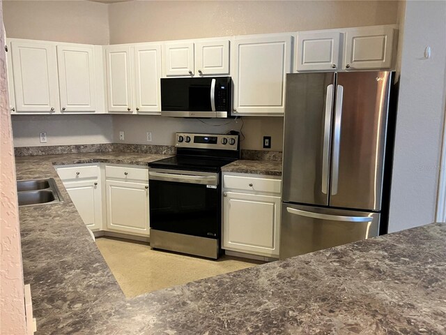 911 N Orange Ave Unit 142, Orlando, FL 32801 - kitchen featuring stainless steel appliances, a sink, dark countertops, and white cabinetry