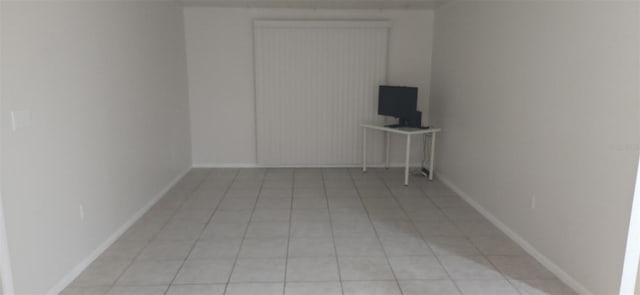 spare room featuring light tile patterned floors and baseboards