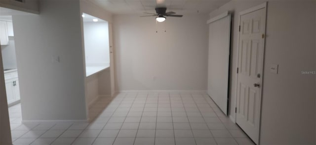 spare room featuring light tile patterned floors, baseboards, and ceiling fan