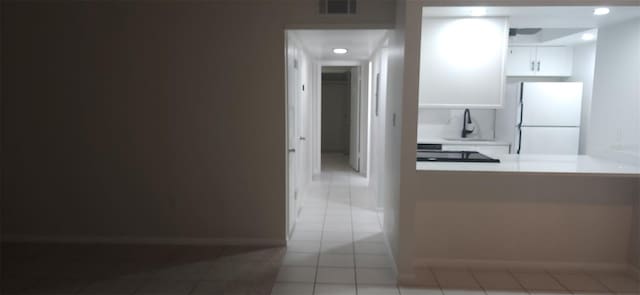 kitchen with visible vents, baseboards, light countertops, freestanding refrigerator, and a sink