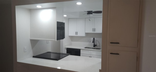 kitchen with a sink, black appliances, light countertops, and white cabinetry