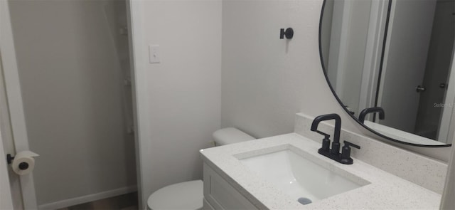 half bathroom with vanity, toilet, and baseboards