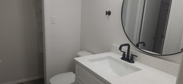 bathroom with toilet, vanity, and baseboards