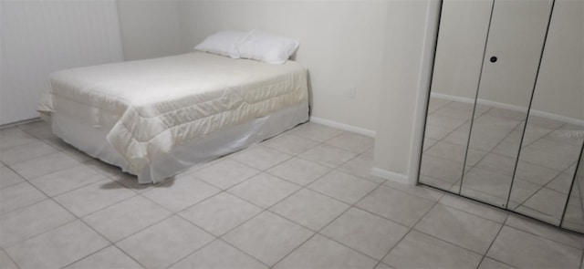 bedroom with light tile patterned floors, a closet, and baseboards