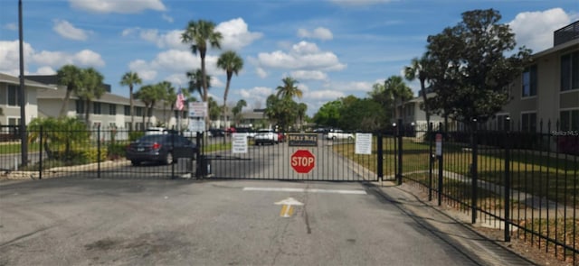 view of street featuring a gated entry, a residential view, traffic signs, and a gate