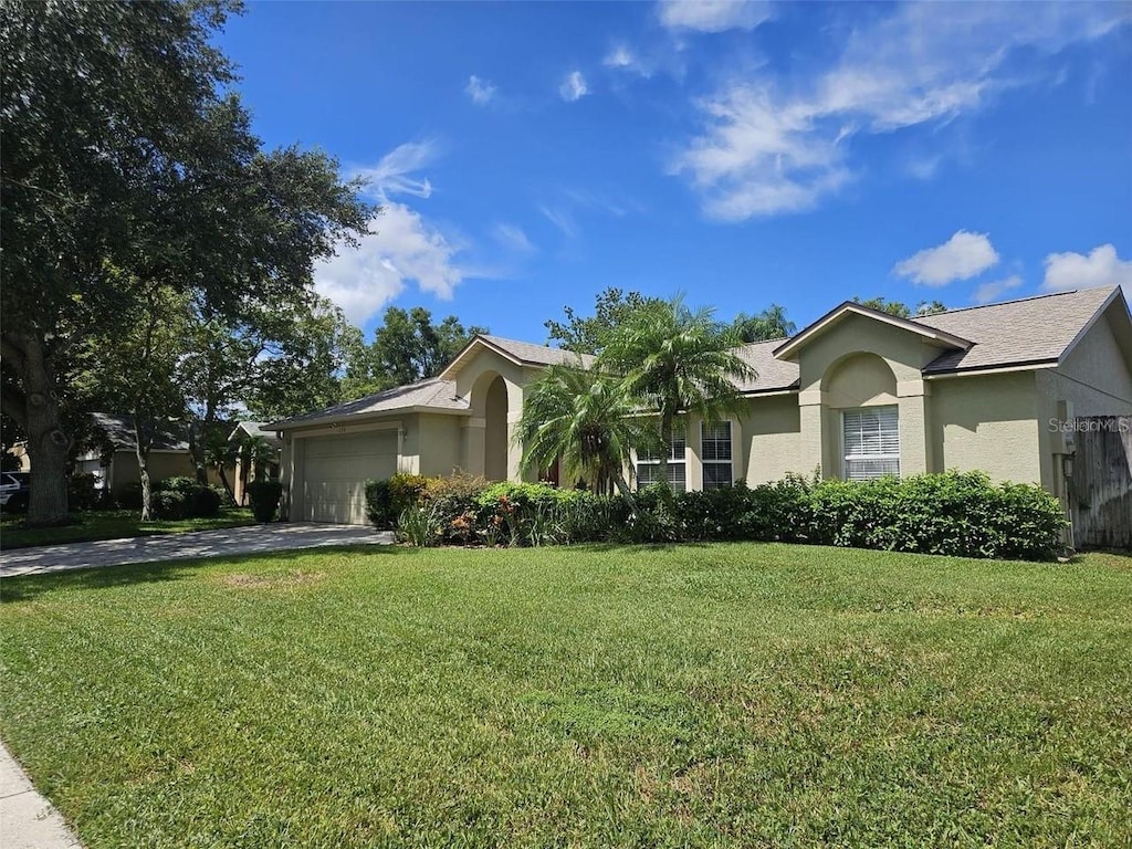 single story home with stucco siding, a front lawn, concrete driveway, and an attached garage