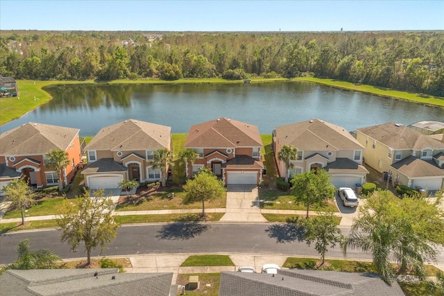 drone / aerial view featuring a residential view, a view of trees, and a water view