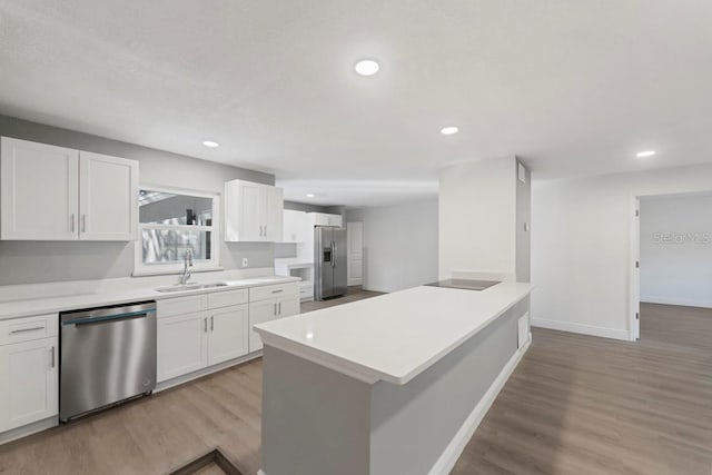 kitchen with a sink, stainless steel appliances, light wood finished floors, and white cabinetry