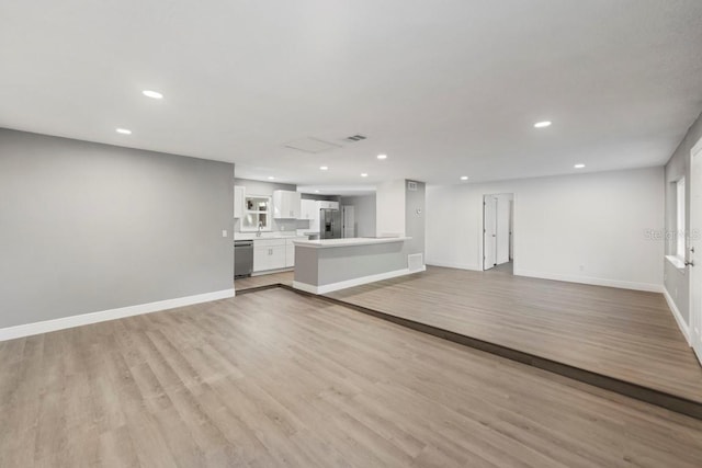 unfurnished living room featuring recessed lighting, light wood-type flooring, and baseboards