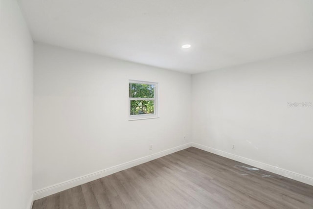 empty room featuring recessed lighting, wood finished floors, and baseboards