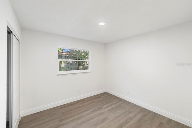 unfurnished bedroom featuring wood finished floors, baseboards, and a closet