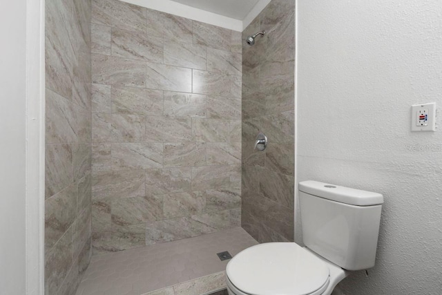 full bath with toilet, a textured wall, and a tile shower