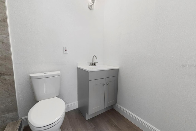 bathroom featuring vanity, toilet, wood finished floors, and baseboards