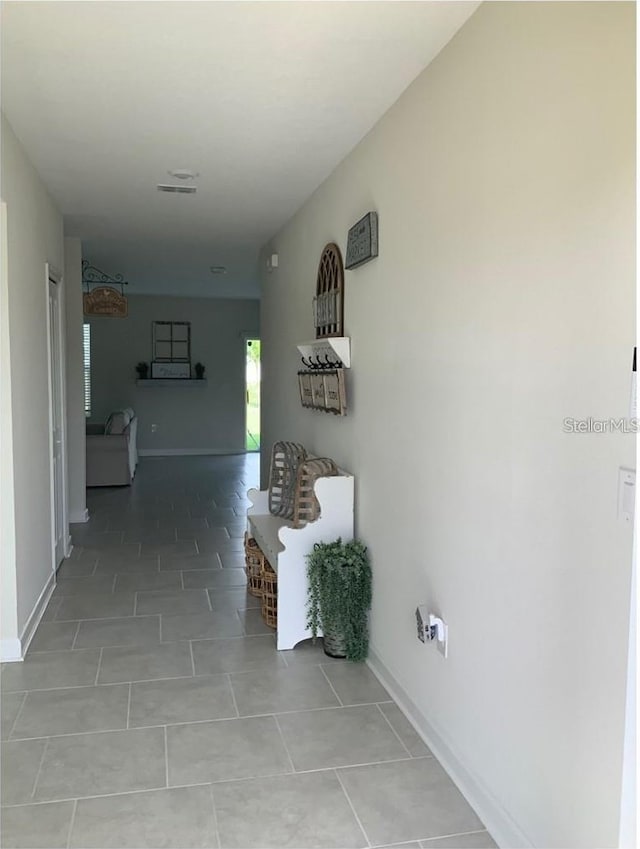 hallway featuring tile patterned flooring, visible vents, and baseboards