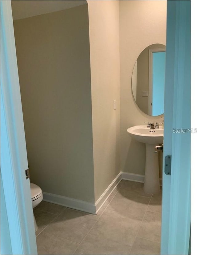 bathroom featuring tile patterned floors, baseboards, and toilet