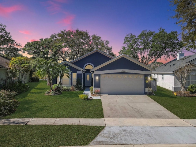 ranch-style house featuring concrete driveway, an attached garage, a front yard, and stucco siding