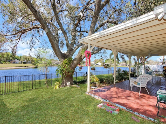 view of yard featuring a patio area, a fenced backyard, and a water view