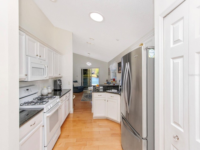 kitchen with lofted ceiling, a peninsula, light wood-style floors, white cabinets, and white appliances