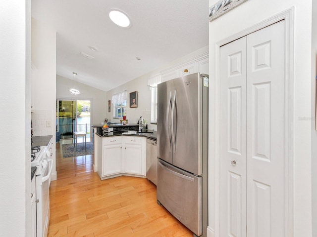 kitchen featuring dark countertops, appliances with stainless steel finishes, a peninsula, and white cabinets