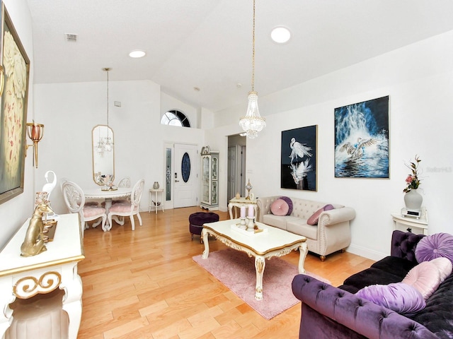 living area with baseboards, high vaulted ceiling, an inviting chandelier, light wood-style flooring, and recessed lighting