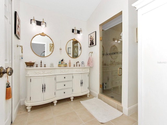 bathroom featuring tile patterned floors, a stall shower, double vanity, and a sink