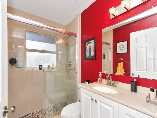 full bathroom with toilet, a stall shower, and vanity