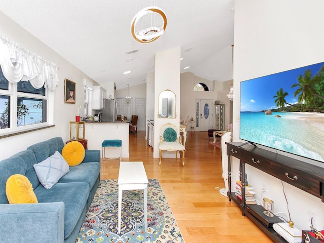 living room featuring light wood finished floors and high vaulted ceiling