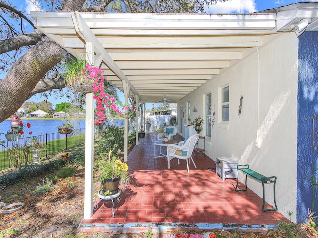 view of patio featuring a water view and fence