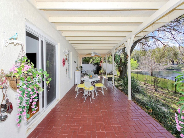 view of patio with a water view, a fenced backyard, a ceiling fan, and outdoor dining space