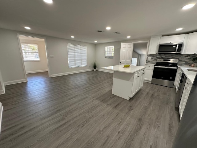 kitchen with backsplash, white cabinets, stainless steel appliances, and dark wood-type flooring