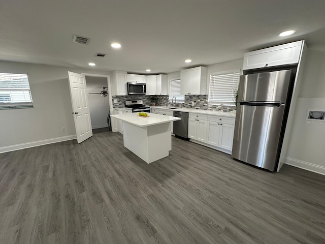 kitchen with visible vents, dark wood-style floors, white cabinetry, appliances with stainless steel finishes, and decorative backsplash