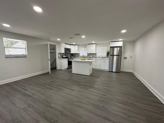 kitchen featuring dark wood-type flooring, open floor plan, stainless steel appliances, white cabinets, and decorative backsplash