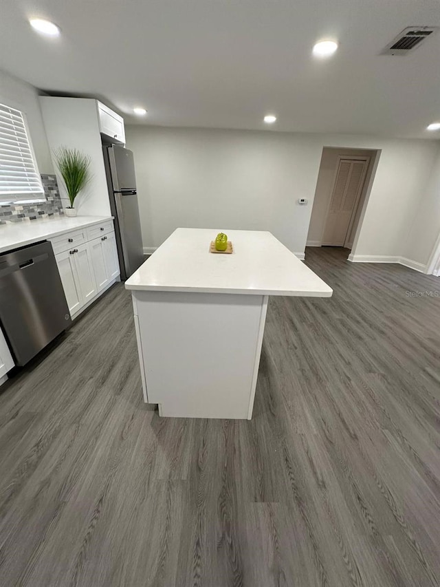 kitchen featuring visible vents, a kitchen island, dark wood finished floors, stainless steel appliances, and white cabinets