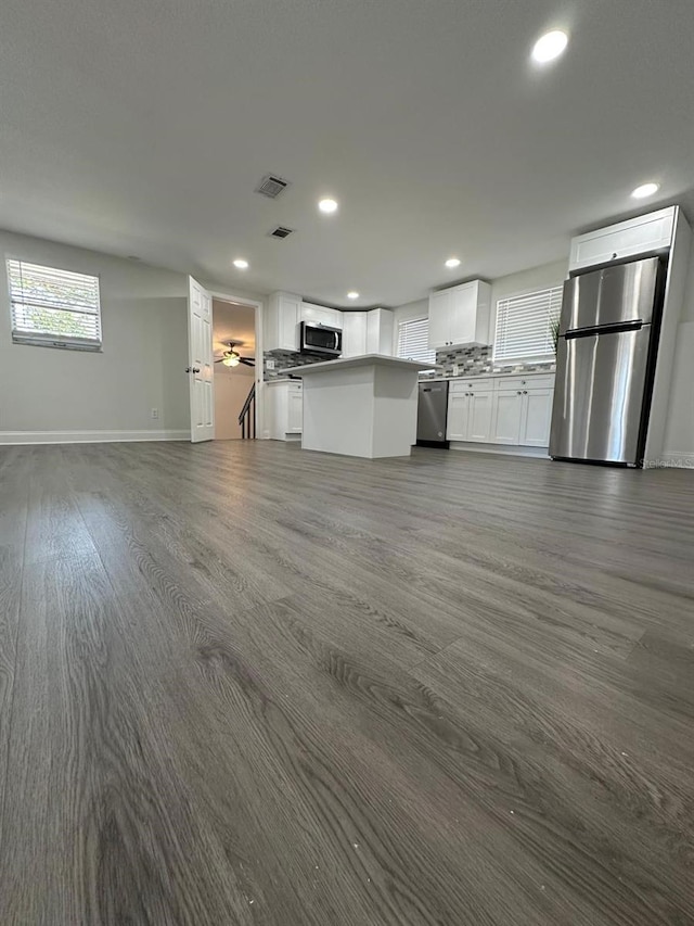 kitchen featuring visible vents, open floor plan, appliances with stainless steel finishes, white cabinets, and dark wood-style flooring