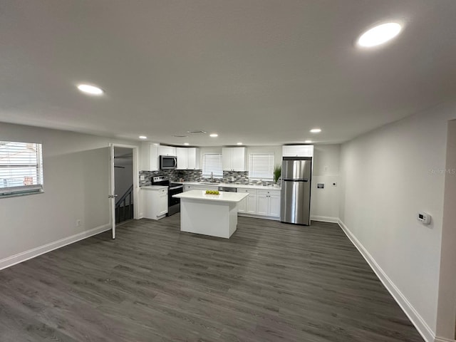 kitchen with a sink, tasteful backsplash, dark wood-style floors, white cabinetry, and stainless steel appliances