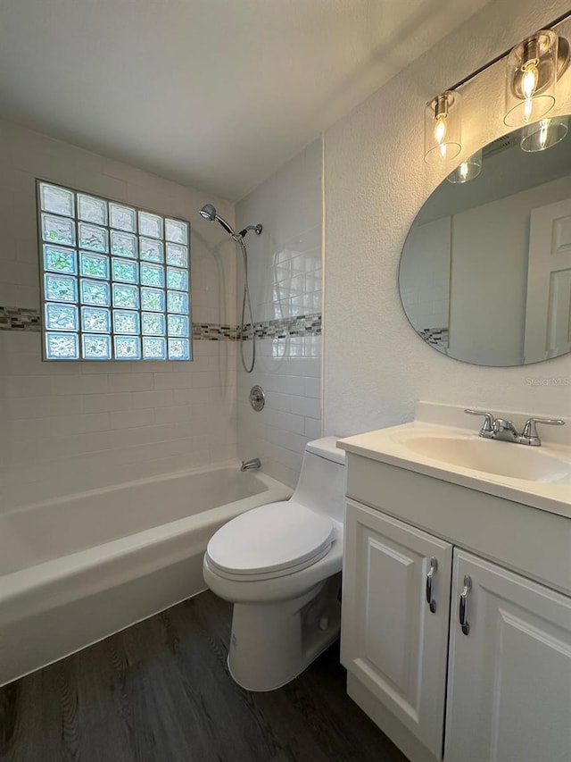 full bathroom with vanity, washtub / shower combination, wood finished floors, toilet, and a textured wall