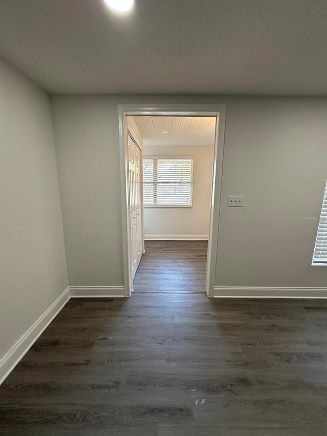 hallway featuring dark wood-type flooring and baseboards