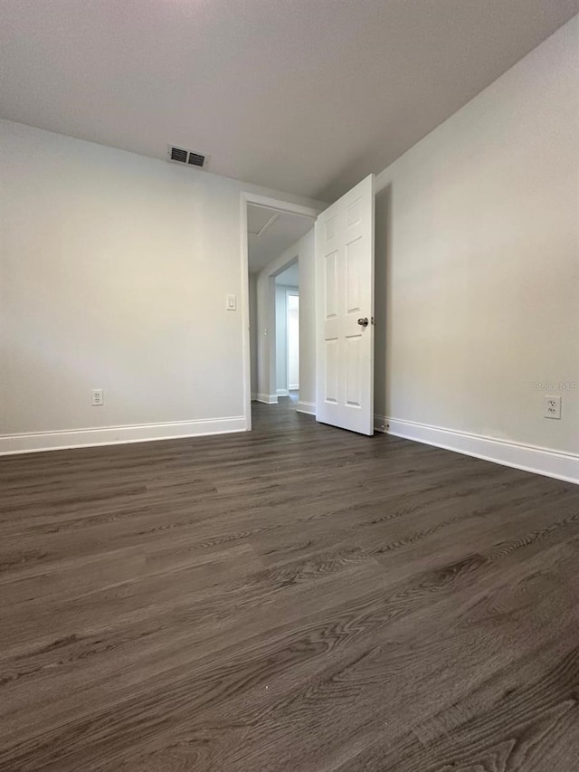 spare room featuring dark wood finished floors, baseboards, and visible vents