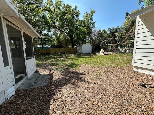 view of yard featuring an outbuilding, a sunroom, a fenced backyard, and a shed