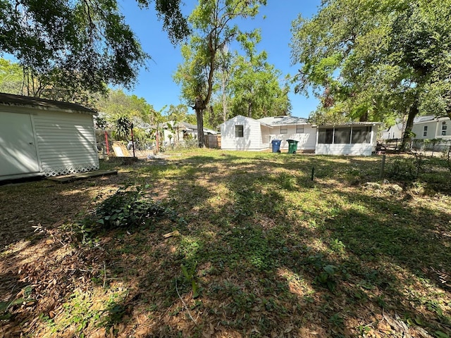 view of yard featuring an outbuilding, a shed, fence, and a sunroom