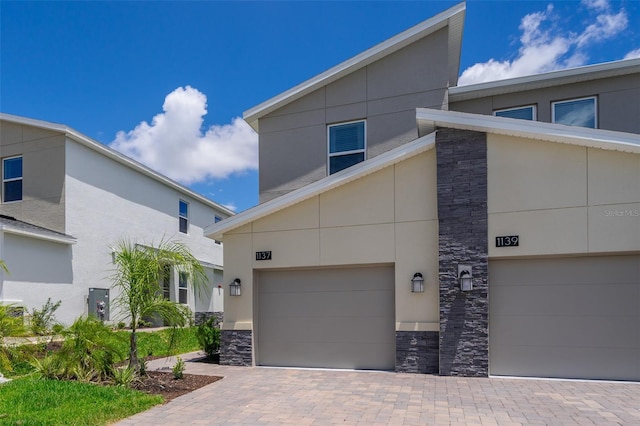 exterior space with stucco siding, stone siding, driveway, and an attached garage