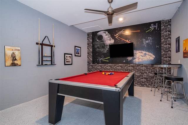 recreation room with billiards, concrete block wall, a ceiling fan, and speckled floor