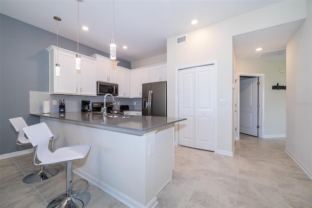 kitchen with visible vents, a sink, tasteful backsplash, stainless steel appliances, and a peninsula